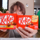 A YouTuber holds up two packages of Kit-Kats, one of which is smaller.